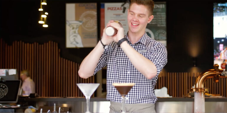 Bar man mixing a cocktail at Nineteen 81 with Digital Designs in background